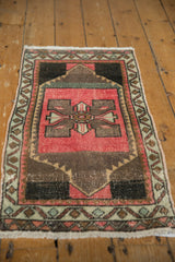 Close-up of distressed vintage Oushak fringe and geometric border in pink and charcoal.