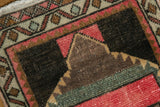 Distressed vintage Oushak rug section with worn pink, charcoal, and sage green tones.