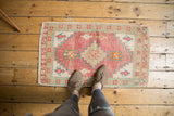 Distressed hand-knotted Oushak rug mat featuring pink, seafoam, and ivory geometric motifs.