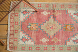 Distressed pink Oushak rug featuring aqua blue stepped patterns and even pile wear.