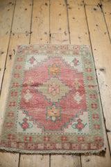 Distressed Oushak mat with pink, seafoam, ivory stepped medallion and lantern motifs.