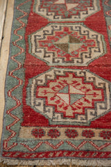 Fringe and geometric vine border with even wear on a cherry red Oushak rug mat.