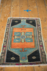 Distressed Oushak rug detail: rust field with 'HT' inscription, teal geometric motif, and fringe.