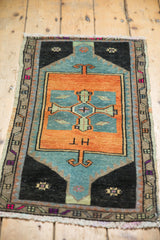 Distressed Oushak rug corner, showing geometric border, dark charcoal, sky blue, and even wear.