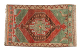 Vintage Oushak rug, featuring a worn geometric medallion in cherry red, seafoam green, beige.