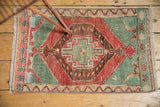 Distressed Oushak rug mat with faded cherry red medallion and seafoam green corners.