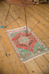 Distressed vintage Oushak rug mat, faded red and green geometric medallion and borders.