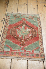 Distressed floral end border with seafoam green motifs on a pale cherry red vintage Oushak rug.