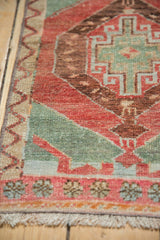 Vintage Oushak rug: pale red, seafoam geometric border, floral motifs, visible wear.