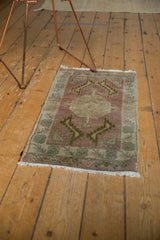 Faded mauve and ivory colors on the textured, distressed pile of a vintage Oushak rug mat.