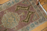 Distressed vintage Oushak rug detail: textured pile with mauve, ivory, and faded blue motifs.