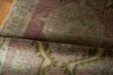Textured pile of a vintage distressed Oushak rug in mauve, dusty gold, and soft blue.