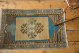 Corner of the vintage Oushak rug showing low pile, brown geometric border, and light fringe.