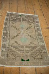 Distressed texture and muted patterns on a vintage Oushak rug, with soft beige and fringed end.