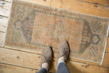 Distressed Oushak rug corner: worn pile, beige, pale apricot, and muted silver tones.