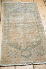 Secured side of a distressed vintage Oushak rug mat with beige and apricot tones.