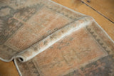 Rolled detail of distressed Oushak rug, highlighting apricot, beige, and oxidized silver pile.