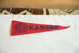 Red felt vintage pennant displaying University of Kansas seal and KANSAS text.