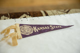 Vintage purple felt Kansas State pennant's pointed tip, showing 'State' text and felt texture.