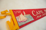 Detail of vintage Cape May felt flag pennant, highlighting yellow binding, red texture, and sailboat graphic.