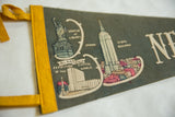 Detail of cream Empire State Building, cityscape, and text on vintage dark grey felt pennant.