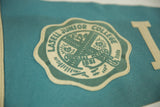 Angled close-up of the vintage Lasell Junior College felt pennant's teal seal and light blue-green body.