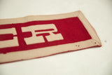 Vintage Exeter felt banner corner with deep red and beige trim, showing light creasing and pinholes.