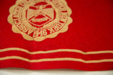 Close-up of the vintage red felt banner's texture, showing the cream-colored 1946 seal.