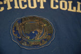 Worn circular emblem with golden stitching on blue Connecticut College felt.
