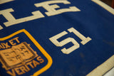 Close-up of cream felt '51' numbers with time-softened hues on the royal blue vintage Yale banner.