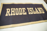 Vintage Rhode Island felt banner showing beige letters on dark blue, with top corner pinholes.