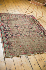 Close-up of antique Karabagh rug showing worn pile, exposed foundation, and tattered ends.