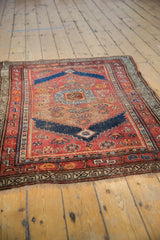 Antique Kurdish rug with a sharp stepped medallion, navy blue and madder red field, showing even pile wear.