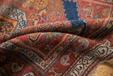Geometric stepped contours on an antique Kurdish rug in madder red and navy blue.