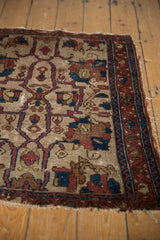 Angled close-up of antique Lilihan rug: ivory field palmettes, indigo vinery, red boteh border.
