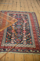 Intricate Kuba rug design featuring geometric plant motifs and subtle serpent forms in charcoal, red, and blue tones.