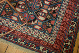 Intact macrame ends and geometric borders of an antique Kuba rug in raspberry, wine, and sky blue.