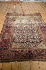 Detail of antique Malayer rug, showing worn madder root red border, floral field, and secured fringe.