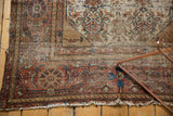 Close detail of antique Malayer rug's worn fringe and tattered side edge.
