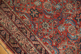 Angled view of an antique Malayer's Herati motif, showing wear to the knot heads in cherry red and navy.