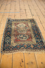 Antique Beshir rug corner showing geometric border, navy, madder red, beige, and wear.