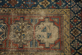 Antique Beshir rug detail: geometric patterns in navy, madder red, beige, with visible foundation etching.