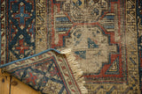 Antique Beshir rug corner: worn geometric motifs, visible fringe, and blue secured edge.