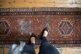 Vintage Karaja runner with madder red field, navy borders, geometric motifs, and visible knot head wear.