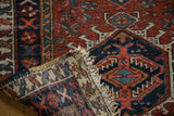 Vintage Karaja runner's beige fringe, secured polychrome selvage, and red, navy geometric pattern.