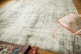 Distressed carpet surface showing worn knot heads, foundation etching, charcoal, purple, and ivory.