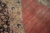 Textured, distressed blush red field and ornate navy border, highlighting wear and new side selvage on this Vintage Tabriz.