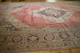 Vintage distressed Jalili Tabriz carpet showing faded blush red field and dark navy medallion.