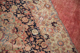Intricate blush red and navy floral patterns on a distressed Vintage Jalili Tabriz rug.