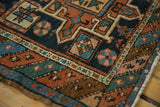 Antique Karaja rug corner showcasing geometric starbursts, floral pinwheels, and polychromatic selvage.